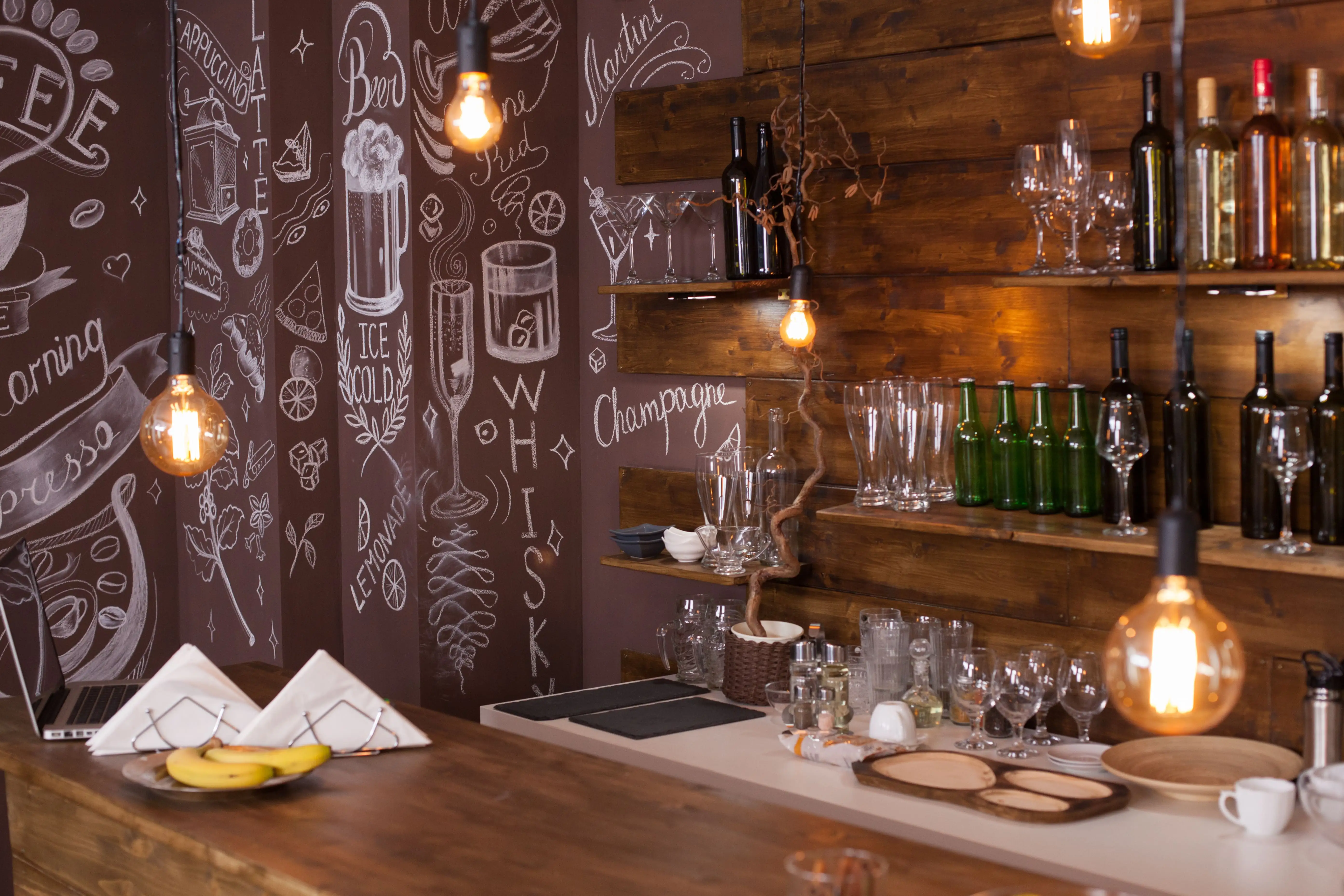 Industrial café interior with hanging wireframe pendant lights above wooden tables and brick walls image